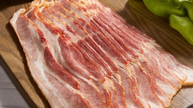 raw strips of Kirkland Signature sliced bacon on a wooden board