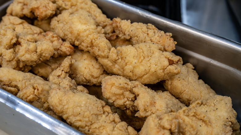 Chicken strips in a commercial kitchen bucket.