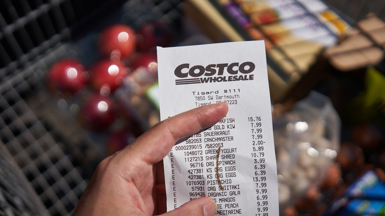 A hand holding a Costco receipt outside store