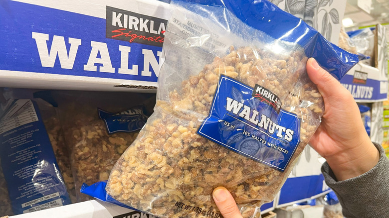 Person's hands grabbing Kirkland Signature walnut bag from bulk box at Costco