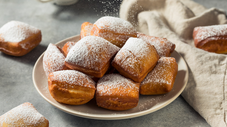 Plate of beignets topped with powdered sugar