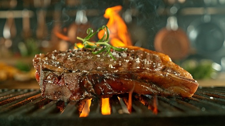 A close-up of a steak on a hot grill over the flames