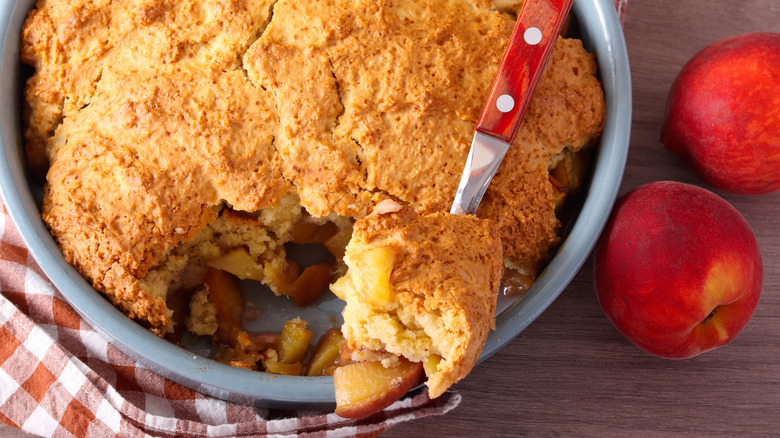 A dish of peach cobbler with a spoon removing a bite