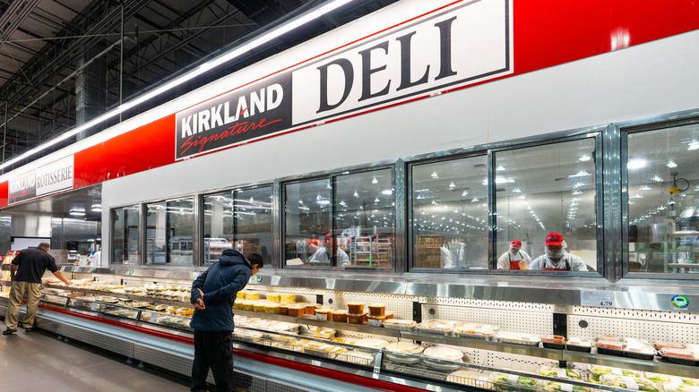 Customers browsing the Kirkland Signature Deli section inside a Costco warehouse
