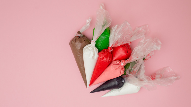 pile of piping bags filled with chocolate, white, and colorful frosting
