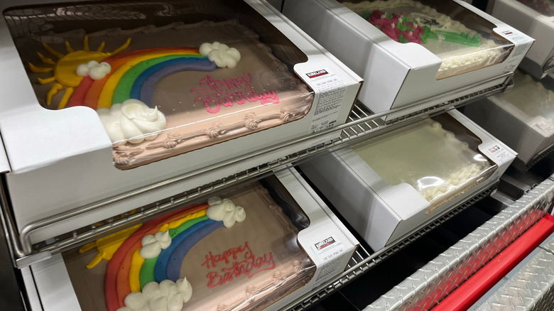 sheet cakes with rainbow decoration in white cardboard boxes on metal shelf