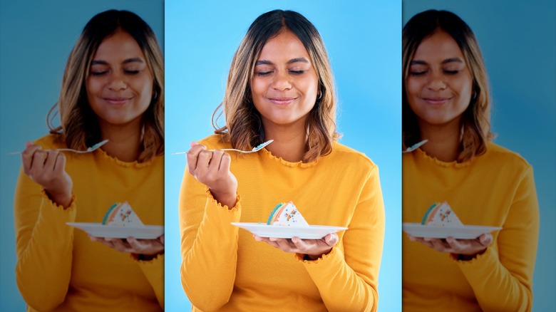 woman smiles and closes her eyes as she tastes a piece of cake