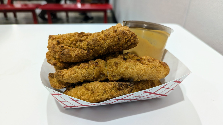 Costco food court chicken tenders in paper boat with dipping sauce container.