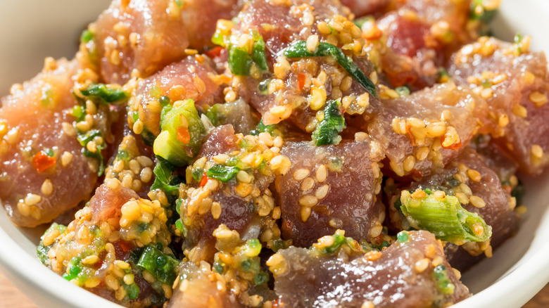 A closeup of a poke bowl with sesame seeds and green onions