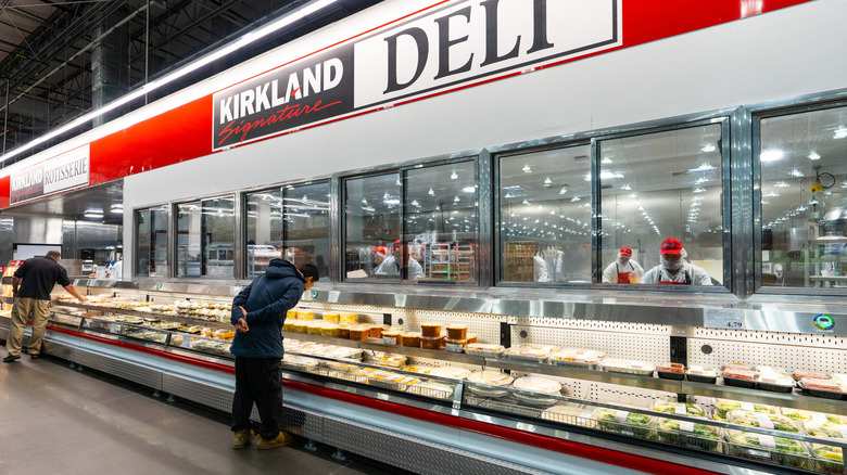 A Costco deli with a customer looking at the food.