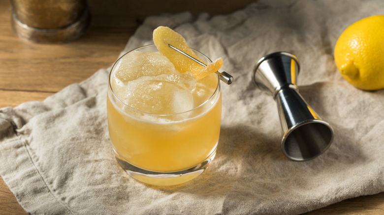 penicillin cocktail on a cloth napkin next to a jigger and a lemon