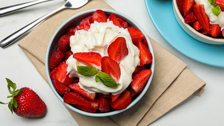 A bowl full of strawberries and whipped cream.