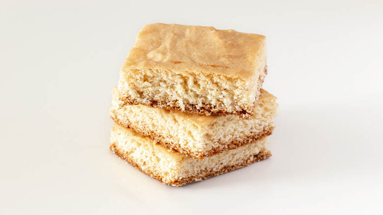 Lemon cake bars stacked on blank background.