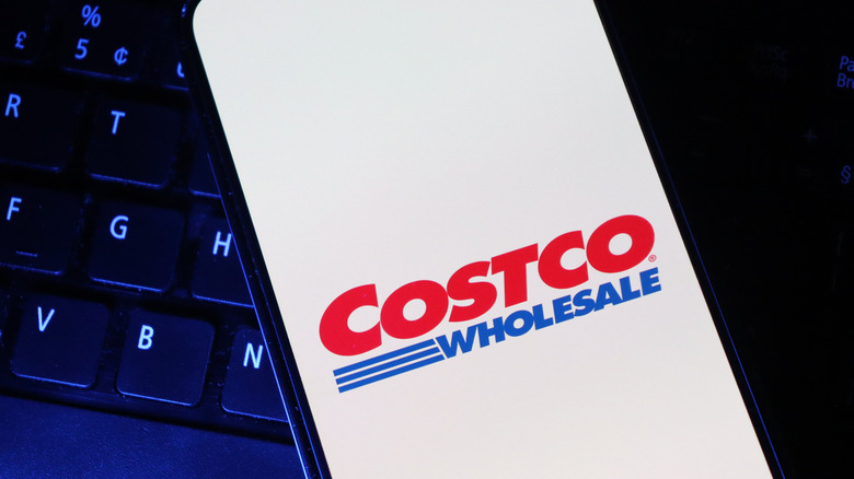 The Costco logo on a smartphone on top of a laptop keyboard.