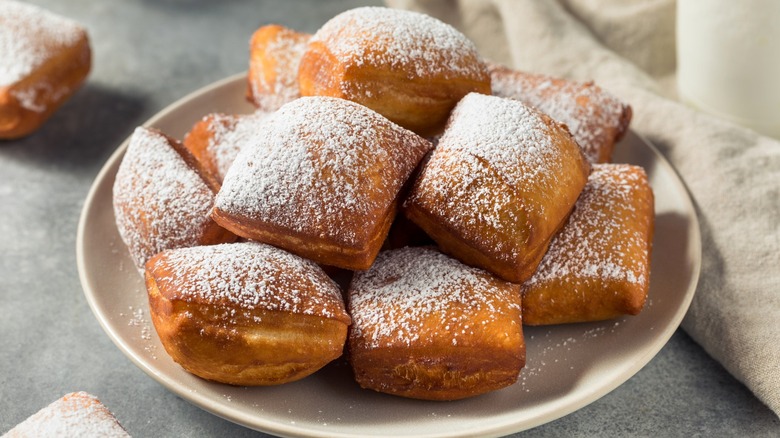 Beignets on white plate topped with powdered sugar