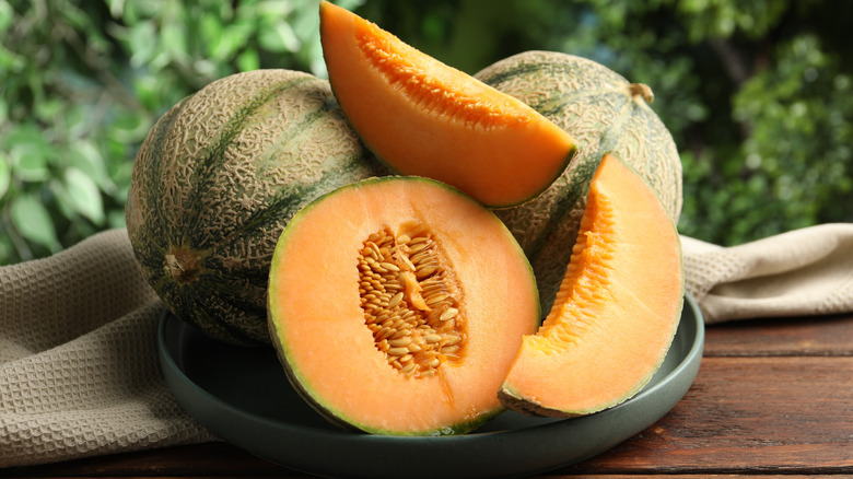 Whole and halved cantaloupe on a plate outdoors
