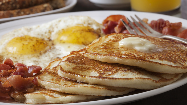 A grand slam breakfast with pancakes, bacon, and eggs at a diner.