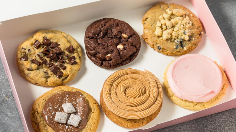 Six popular cookies from the dessert chain Crumbl inside a large pink and white box.