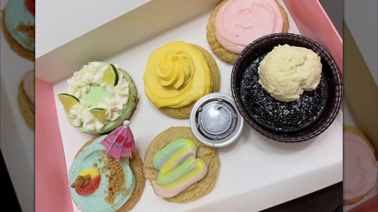 An assortment of six of the special Beach Week desserts from Crumbl inside a pink and white box