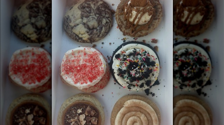 Crumbl Fan Favorites cookies in a box, featuring Marbled Cheesecake Stuffed, Oreo Birthday, Twix, Biscoff Skillet, Snickerdoodle Cupcake, Strawberry Ice Cream Bar