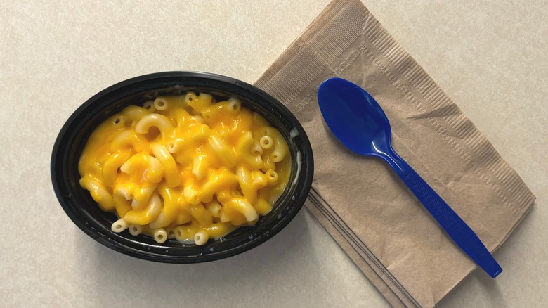 Macaroni and cheese in black dish next to blue spoon on brown napkin
