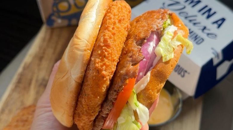 hand holding a CurderBurger in front of a Culver's cardboard carton