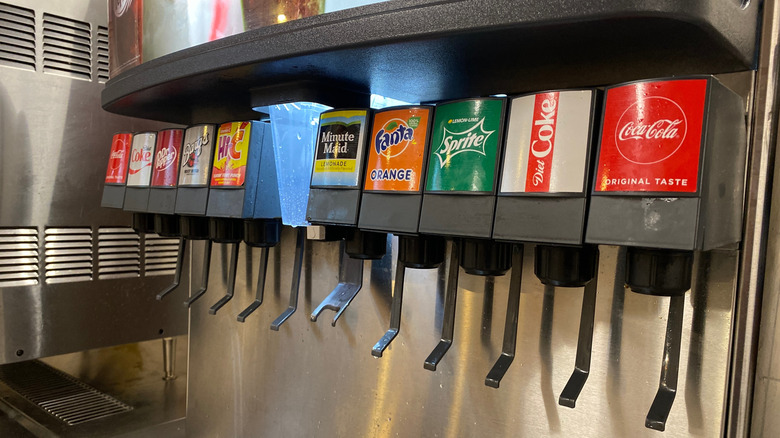 A row of soda fountain dispensers offering various major soda brands