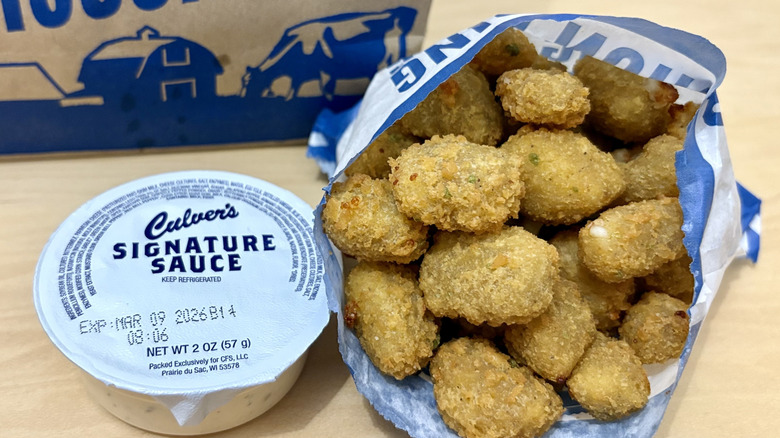 A bag of Culver's jalapeno cheese curds with a container of signature sauce