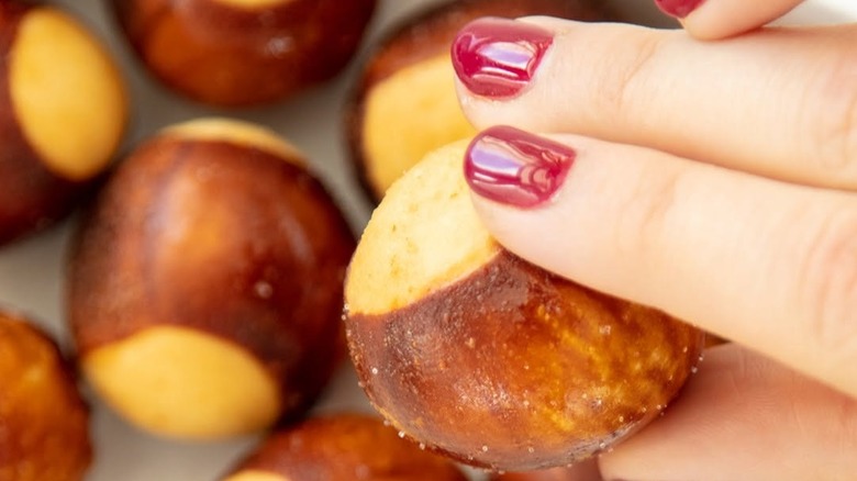 Hand with red painted finger nails holding pretzel bites