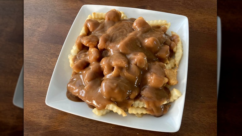 Culver's crinkle fries and cheese curds topped with gravy on a square white plate