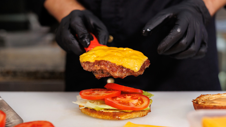 A cook preparing a burger.