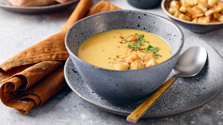 Potato soup next to spoon and napkin
