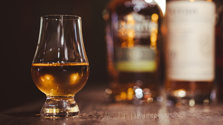 Whiskey in a Glencairn glass with bottles in the background