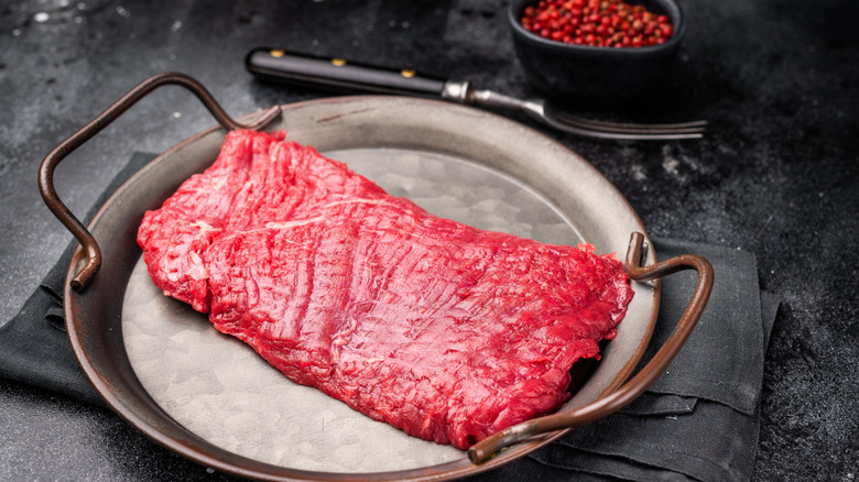 Uncooked flank steak on a metal platter