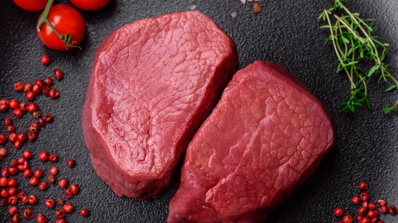 Raw beef eye steak round with salt, spices and herbs prepared for grilling
