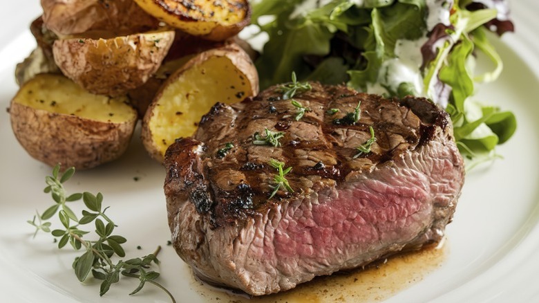 Plate of grilled steak with salad and potatoes