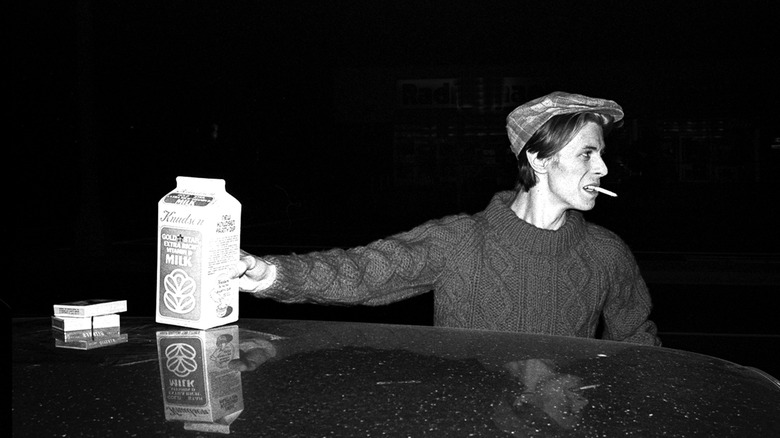 A young David Bowie smoking a cigarette and holding a carton of milk in the '70s