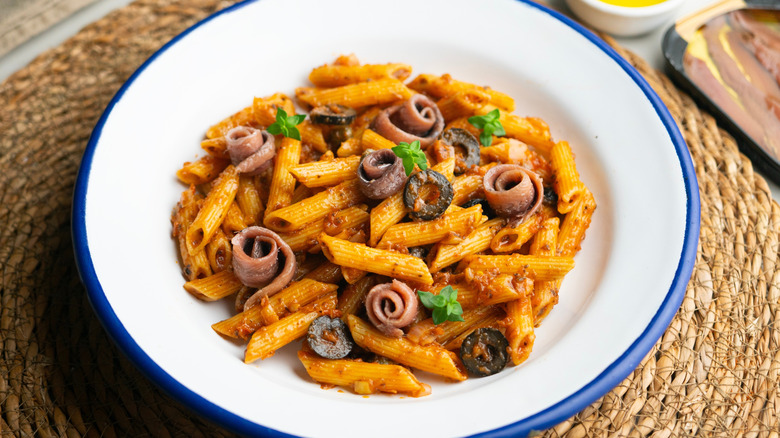 Penne pasta puttanesca on a white plate
