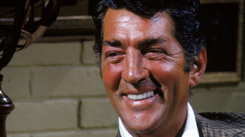 Dean Martin smiling in front of brick wall