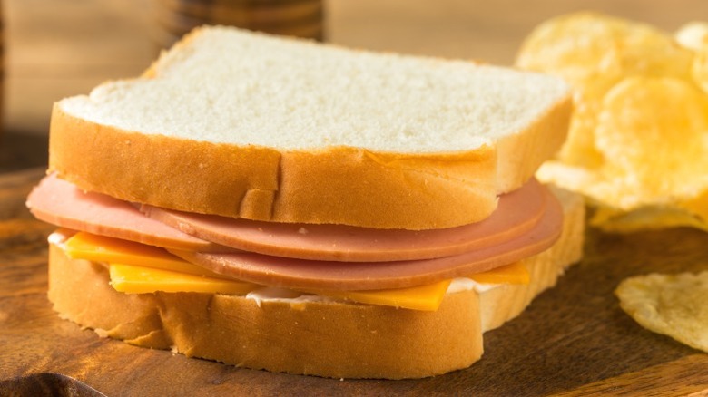 A bologna and cheese sandwich with potato chips
