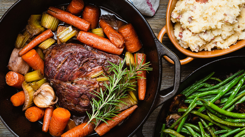 Pot roast in a cast iron pan served with mashed potatoes and green beans