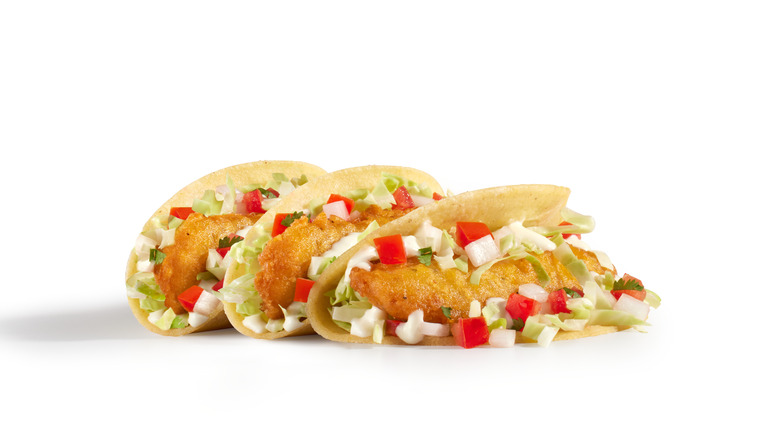 Del Taco fish tacos in a row with a white background.
