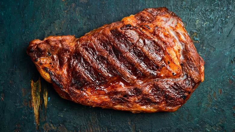 Cooked steak with grill marks on a slate background