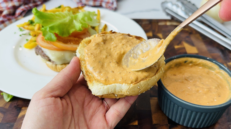 Spreading burger sauce on a burger bun