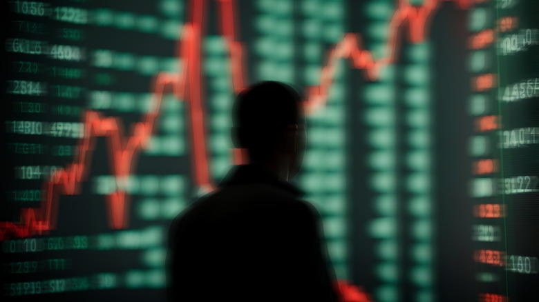 Sillhouette of a person in front of stock market ticker showing price fluctuations