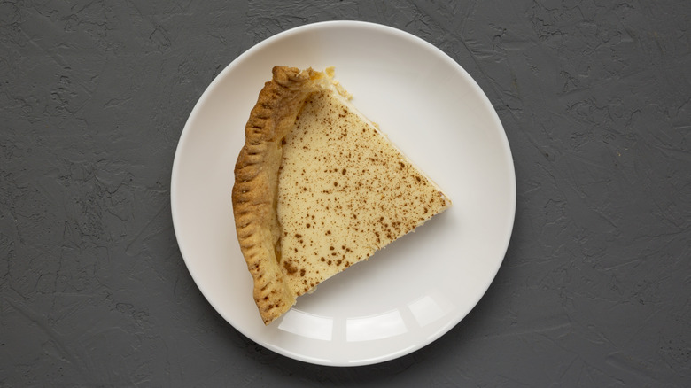 A piece of custard pie on a white plate