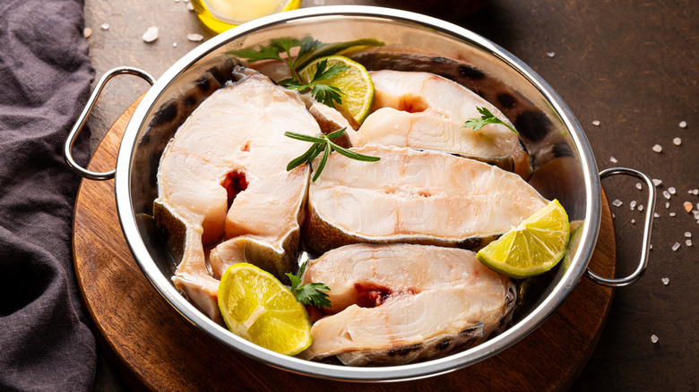 Catfish filets in a metal pan with herbs and lemon