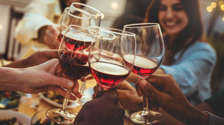 Friends toast glasses of red wine at a dinner table