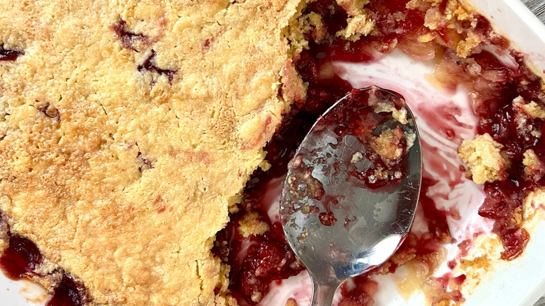 Cherry Dump Cake in a baking tray with a portion scooped out with a metal spoon