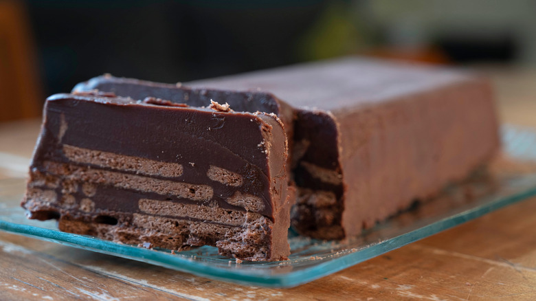 A long chocolate and biscuit log cake known as Hedgehog slice on a glass serving plate